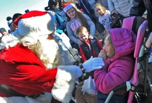 Santa, left, greets an emotional Sydney Kennedy, 19, of Quincy, right, at Pageant Field in Quincy, Saturday, Nov. 26, 2022.